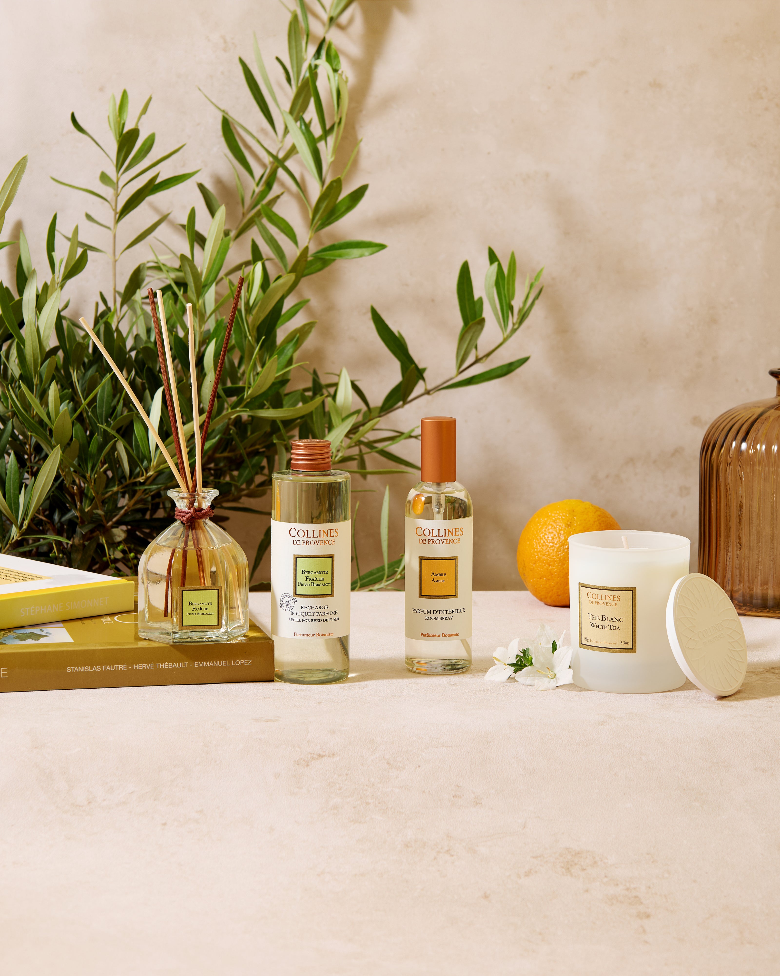 Collines De Provenece products on a table with a plant, an orange in the background