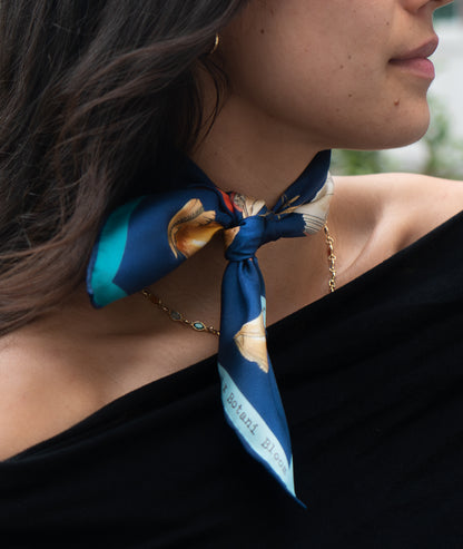 Woman wearing a blue floral scarf around her neck with a blurred background