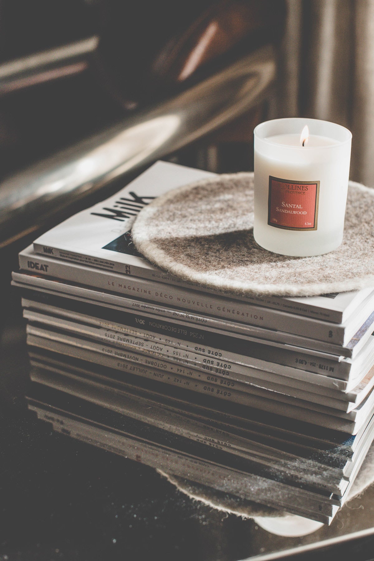 Collines de provence sandalwood scented candle on a stack of books with a textured surface