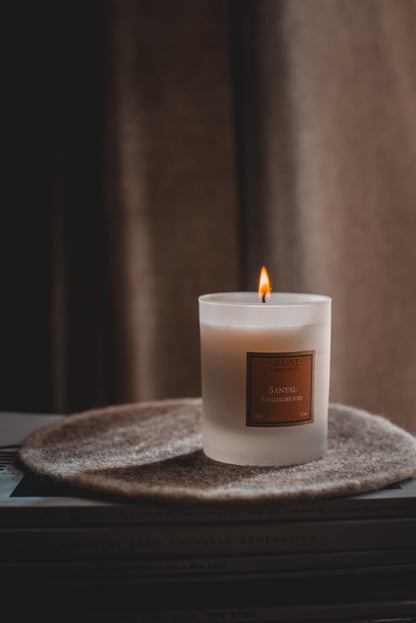 Collines de Provence Sandalwood Scented Candle with a label on a textured surface with a blurred background