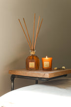 Collines de Provence reed diffuser and scented candle on a wooden surface with a neutral background