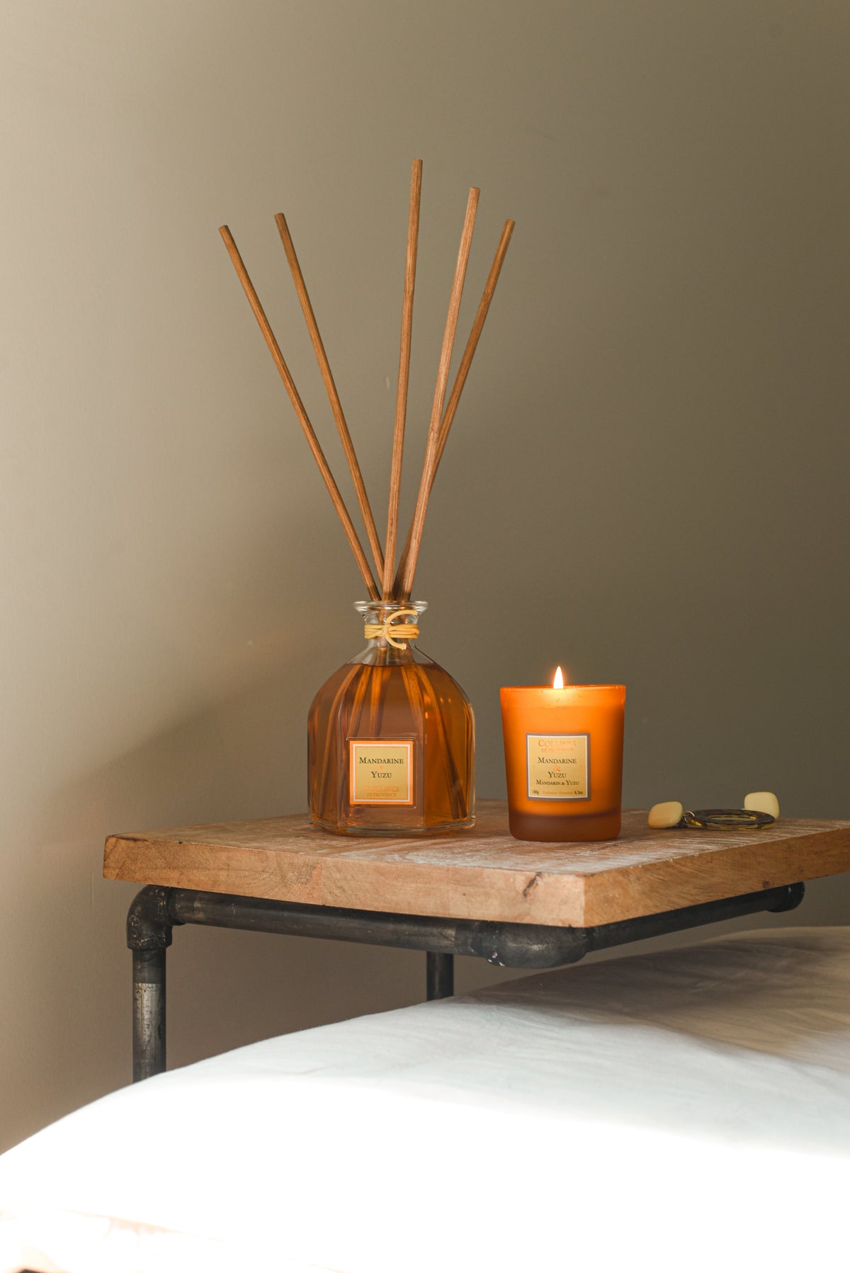Collines de Provence reed diffuser and scented candle on a wooden surface with a neutral background