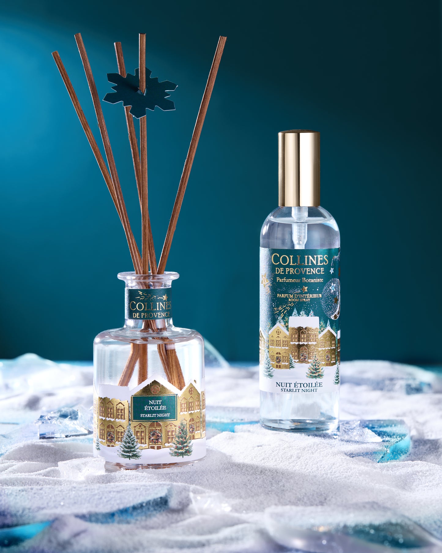 botani bloom reed diffuser bottles with wooden sticks and room spray on a textured surface with a blue gradient background