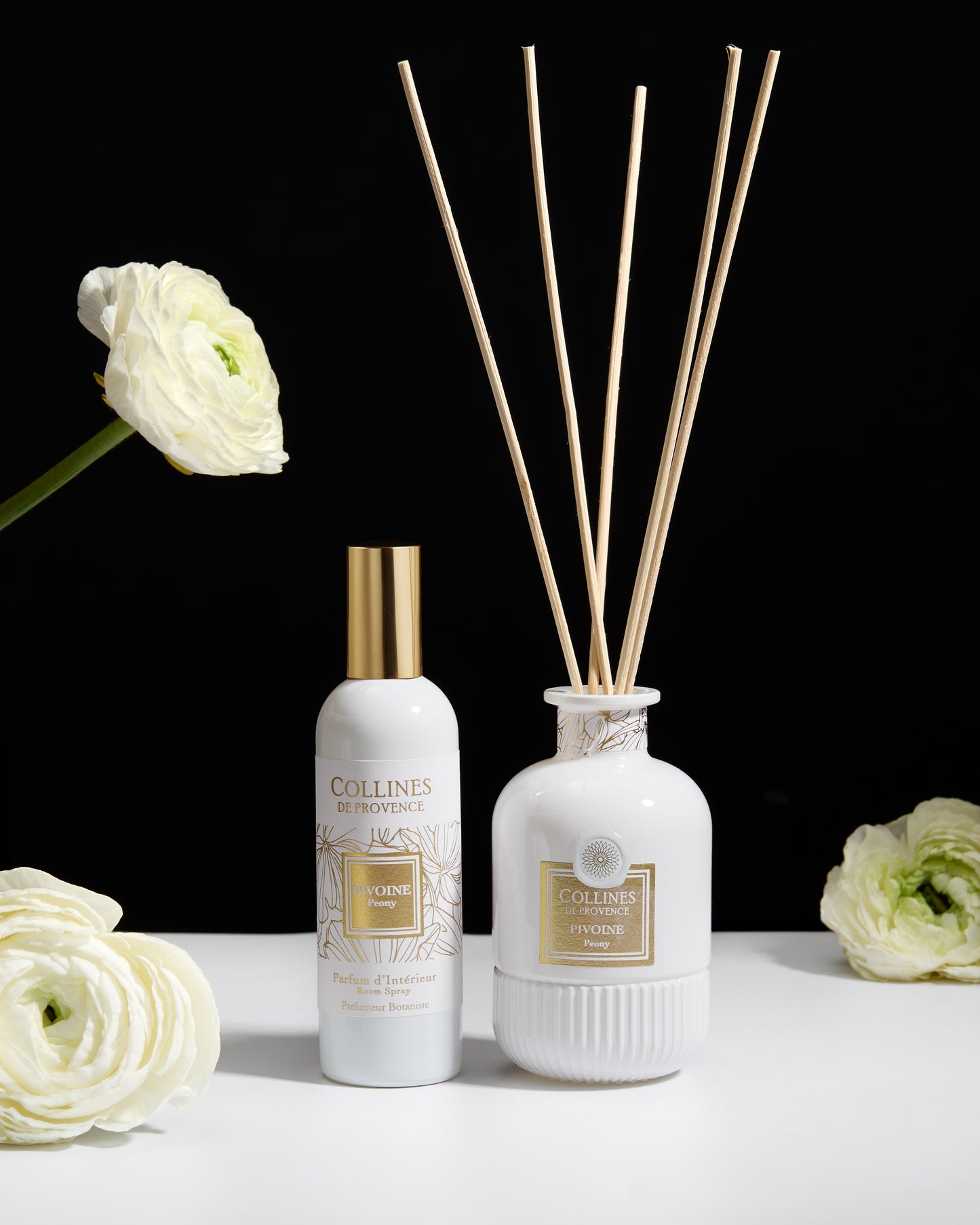 Collines de Provence peony diffuser with reeds, room spray, and flowers on a white surface