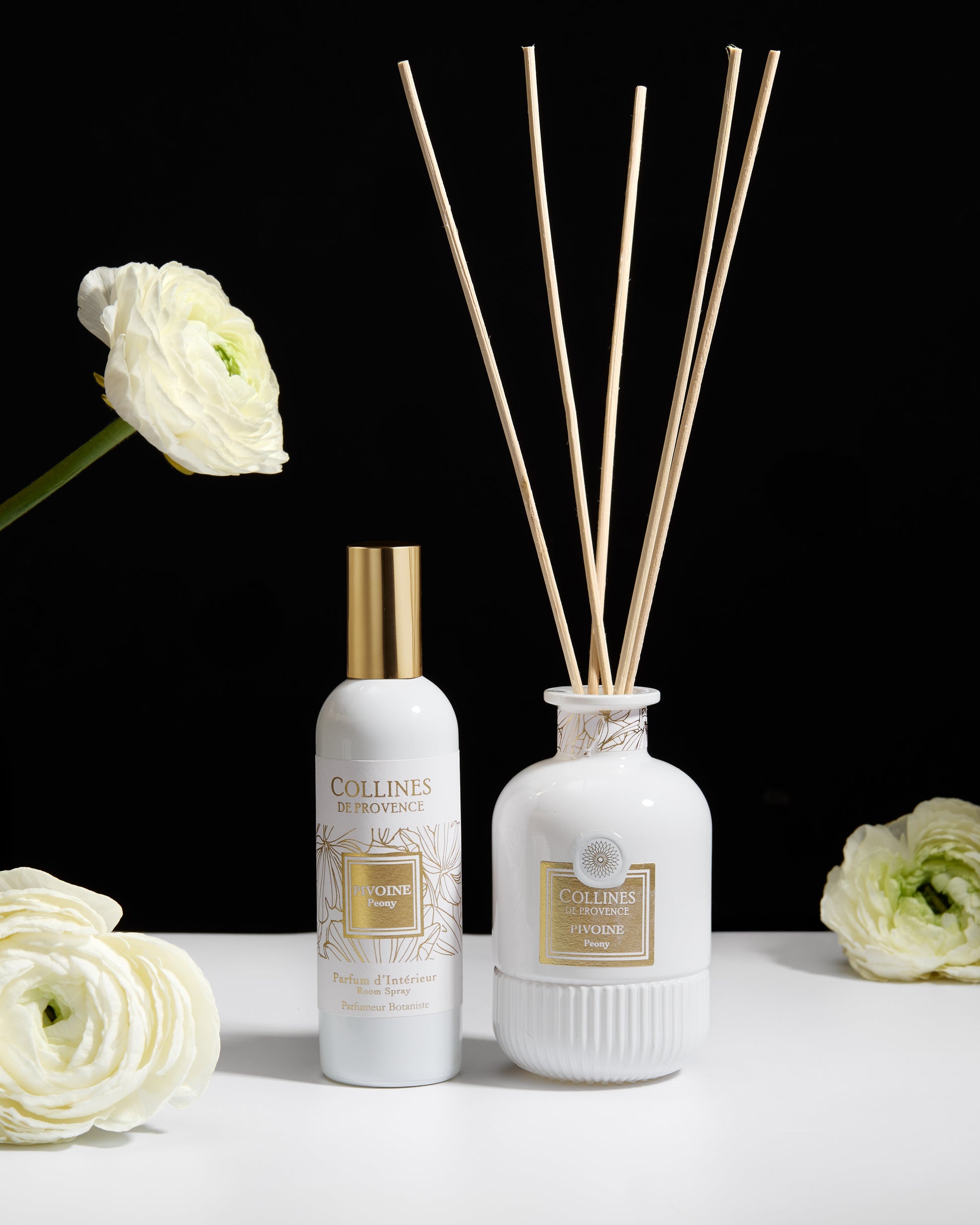 Collines de Provence Peony Room spray and diffuser bottle with reeds and flowers on a white surface