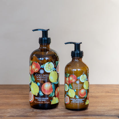Citrus Orchard glow bundle by Collines De Provence, composed of a bottle of Citrus Orchard glow liquid soap and a bottle of Citrus Orchard glow body lotion, front view, on a wooden surface