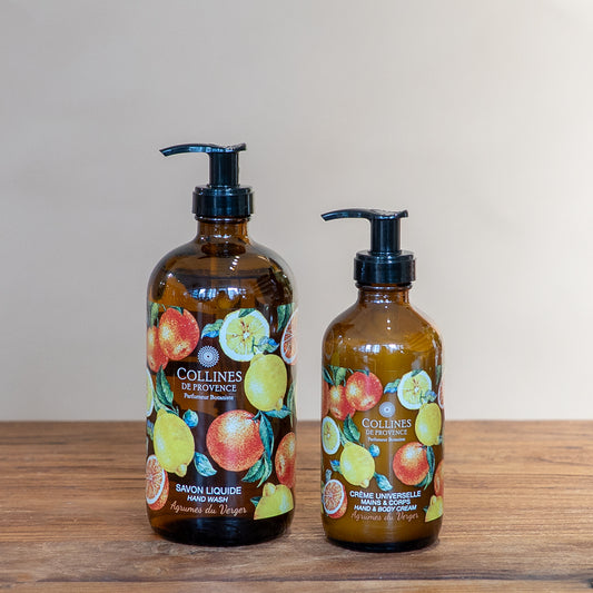 Citrus Orchard glow bundle by Collines De Provence, composed of a bottle of Citrus Orchard glow liquid soap and a bottle of Citrus Orchard glow body lotion, front view, on a wooden surface