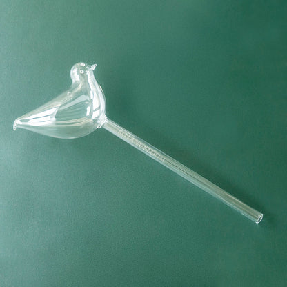 A clear glass bird shaped watering bulb designed to hold water, front view