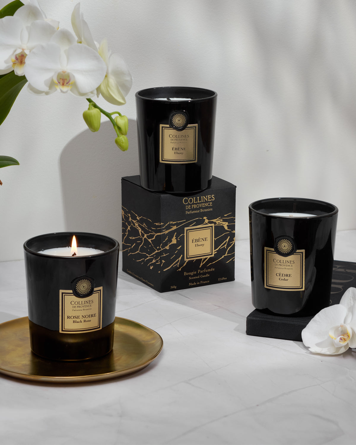 Black Rose scented candles, alongside their packaging and orchid flowers for decoration.