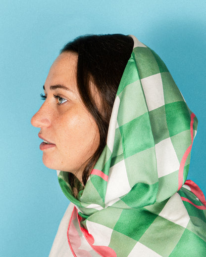 Woman wearing a green and white checkered scarf against a blue background