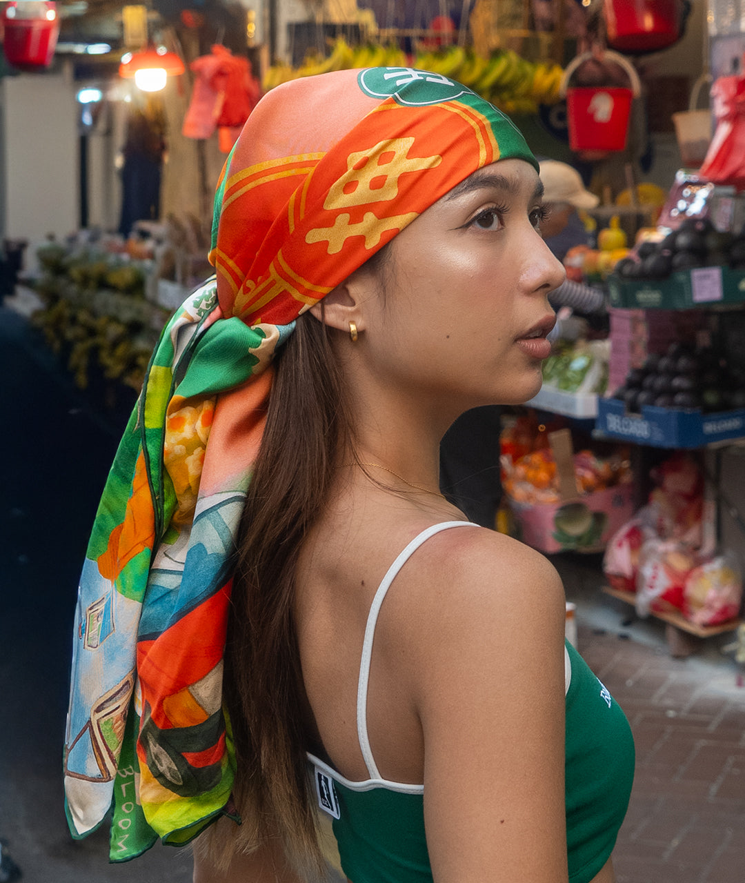 Woman wearing a colorful Botani Bloom Hong Kong Heritage headscarf in a market setting
