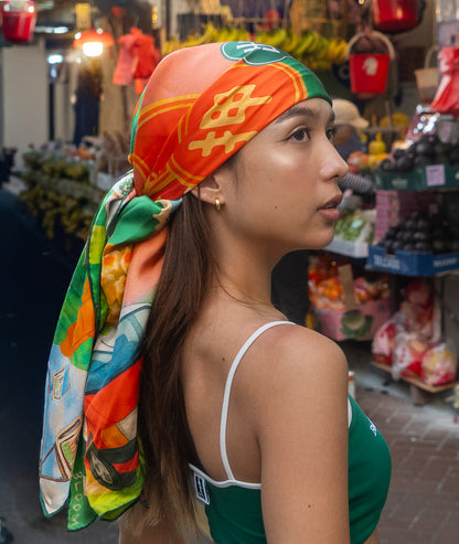 Woman wearing a colorful Botani Bloom Hong Kong Heritage headscarf in a market setting