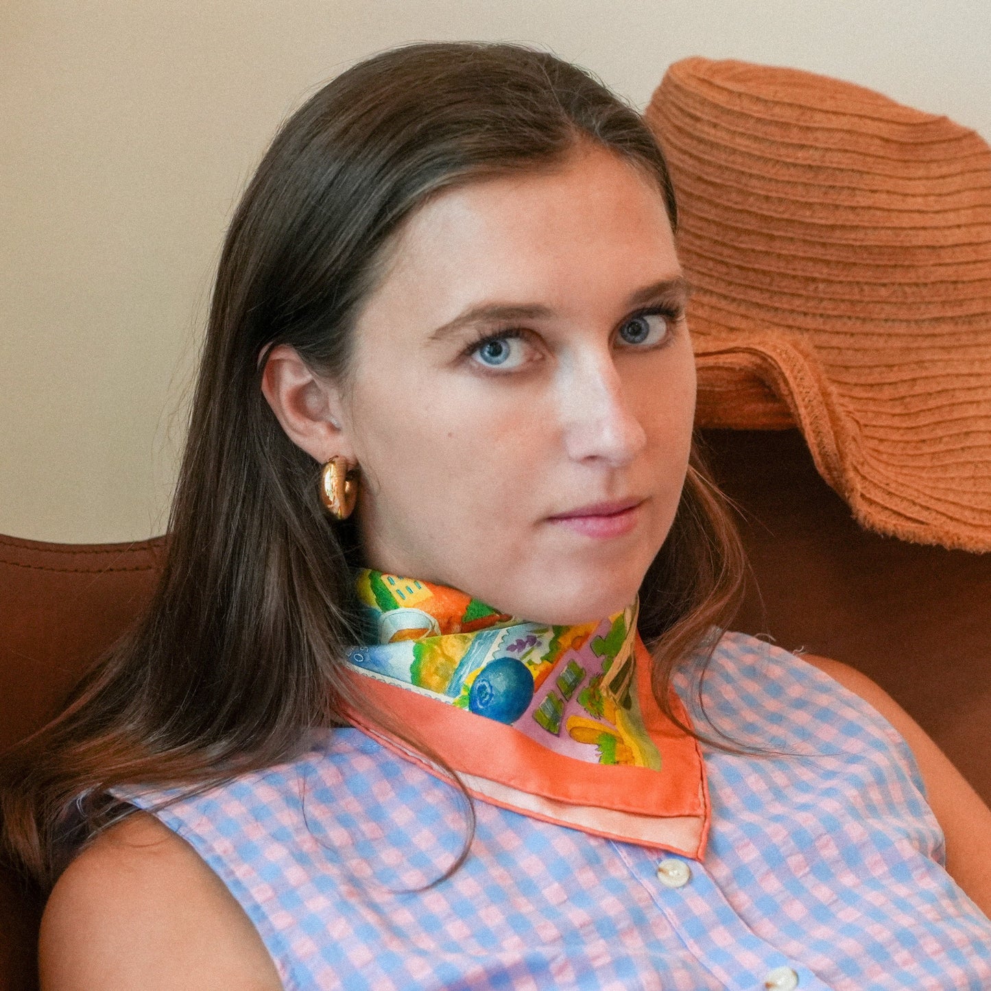 Woman wearing a colorful scarf sitting on a brown chair.