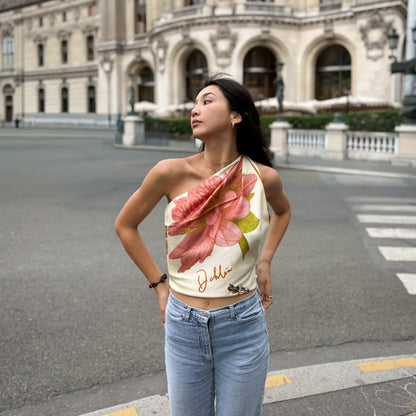Woman wearing a floral botani bloom silk scarf as a top and jeans standing on a street with a classical building in the background