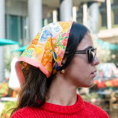 Woman wearing a colorful scarf and sunglasses with a blurred outdoor background