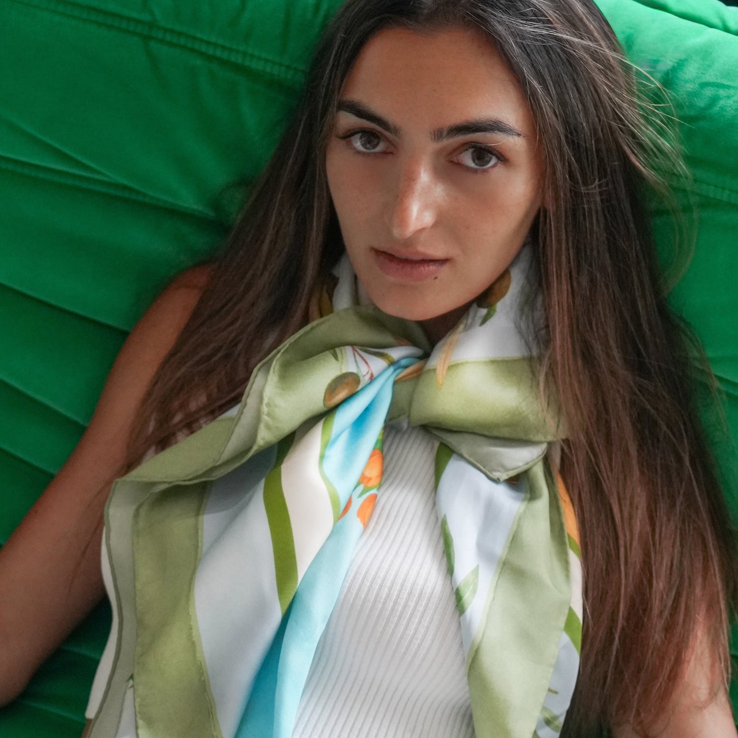 Woman wearing a colorful scarf with a green background