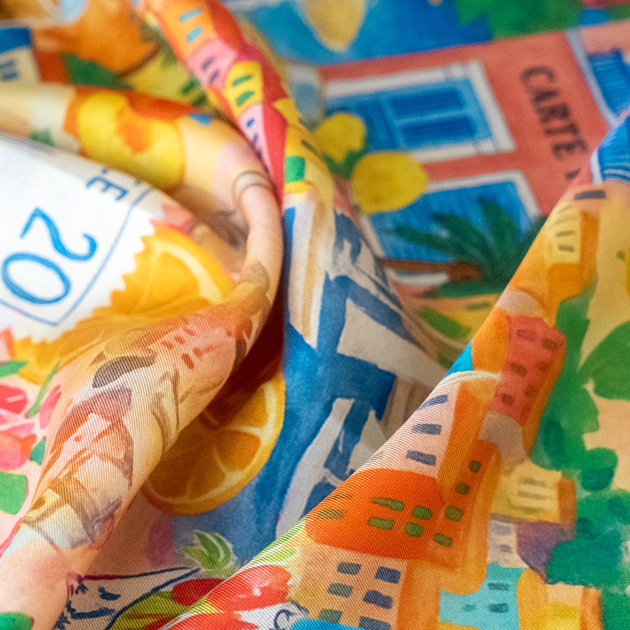 Colorful scarf with tropical patterns and text, featuring oranges and a building.
