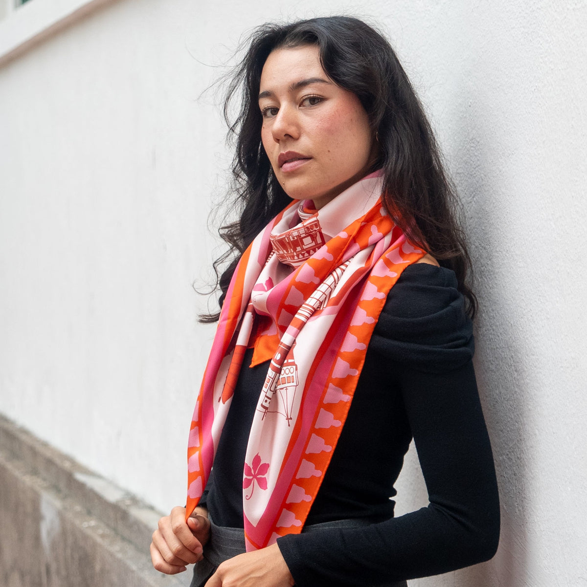 Woman wearing a colorful botani bloom silk scarf against a white wall