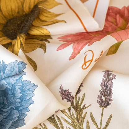 Close-up of floral-patterned silk scarf with sunflower, lavender, and other designs.