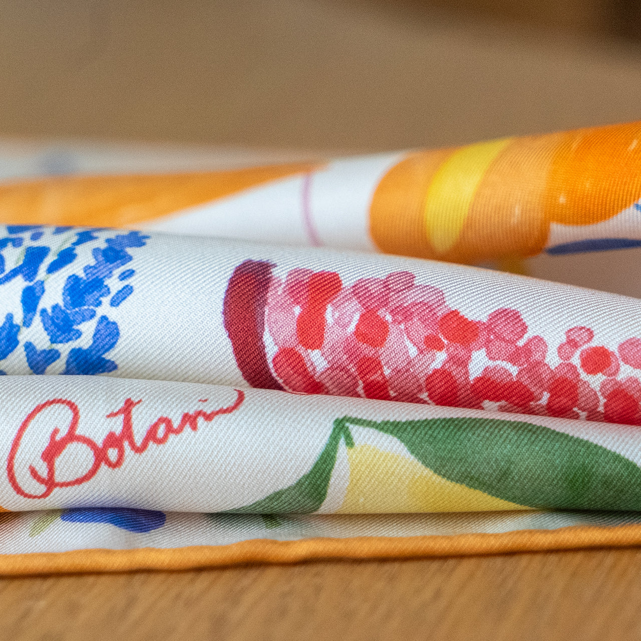 folded botani bloom scarf with floral patterns on a wooden surface