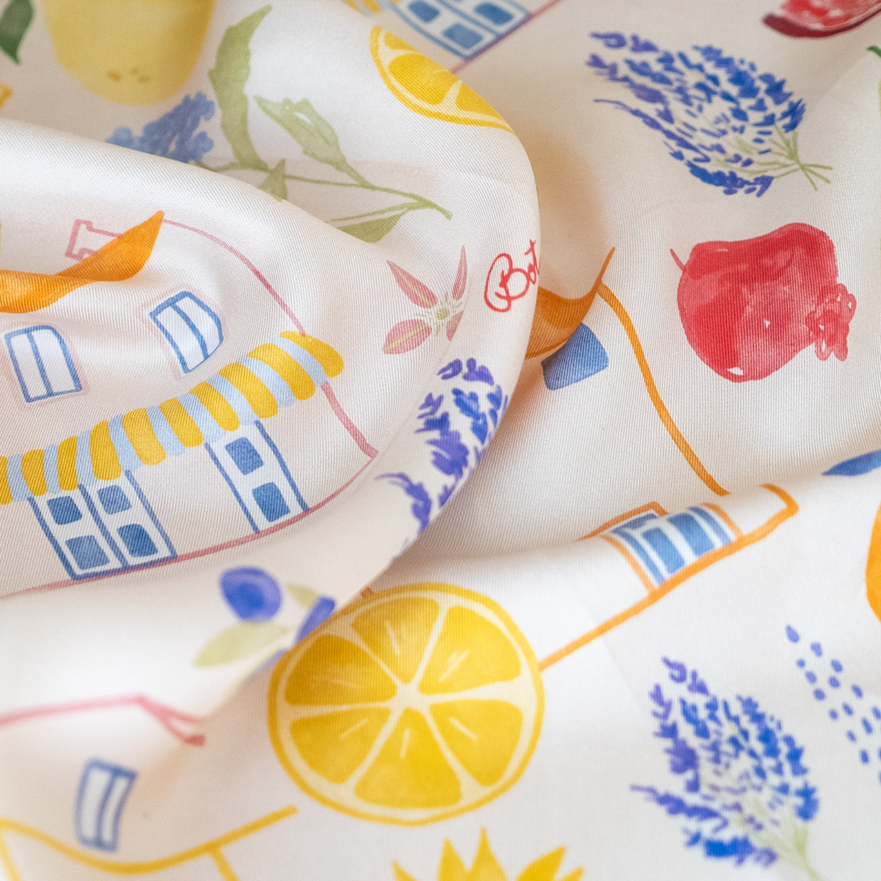 Close-up of botani bloom silk scarf with colorful prints including houses, lemons, and lavender.