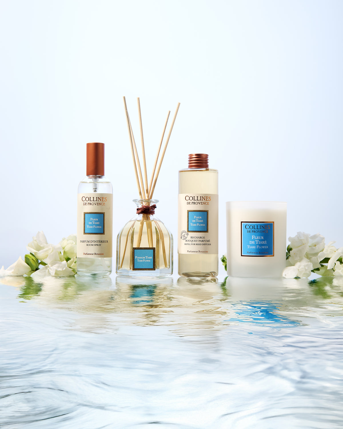 Collines De Provence tiare flower diffuser, room spray, diffuser refill, and candle with floral arrangement on water