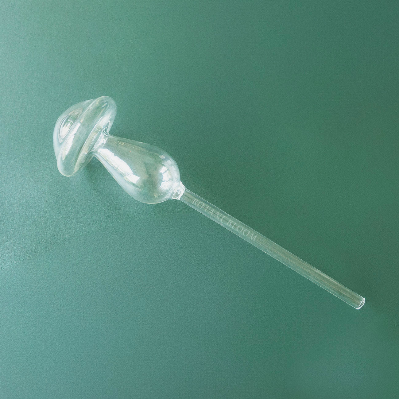 A clear glass mushroom shaped watering bulb designed to hold water, front view