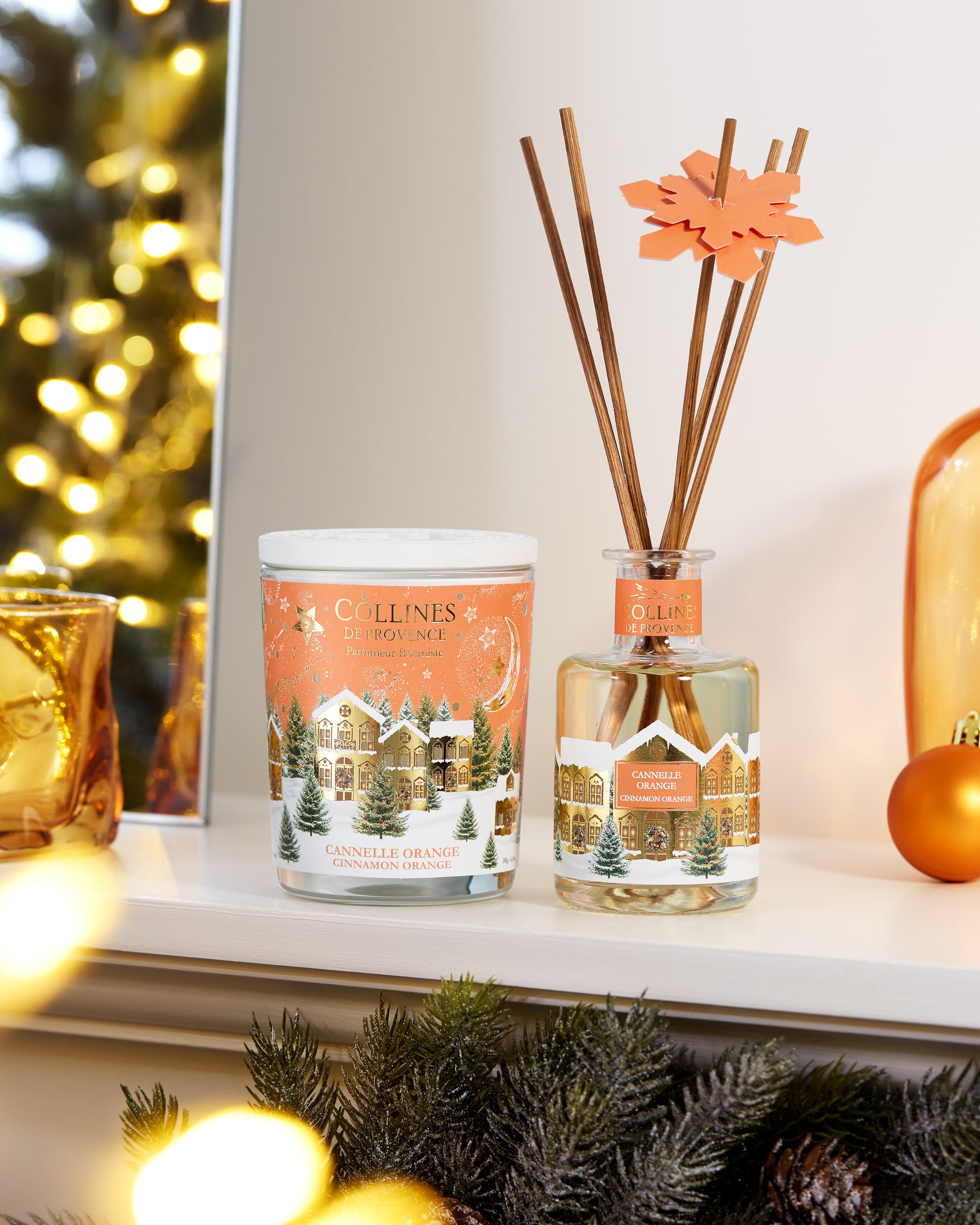 Collines de Provence cinnamon orange scented candle and reed diffuser on a christmas decorative surface with festive background