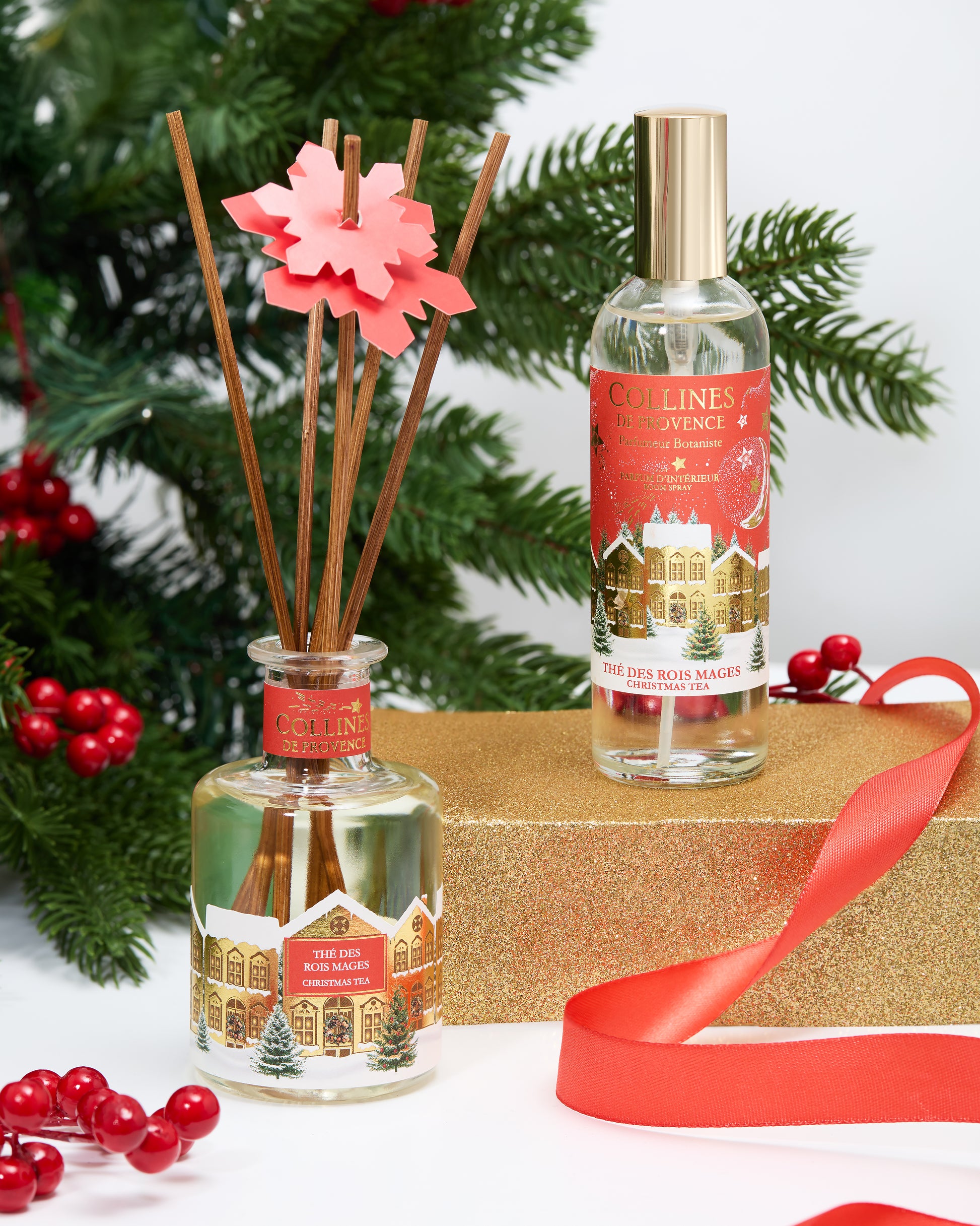 Botani bloom christmas tea reed diffuser and room spray with Christmas-themed labels on a decorative surface with greenery and red berries