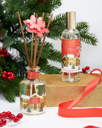 Botani bloom christmas tea reed diffuser and room spray with Christmas-themed labels on a decorative surface with greenery and red berries