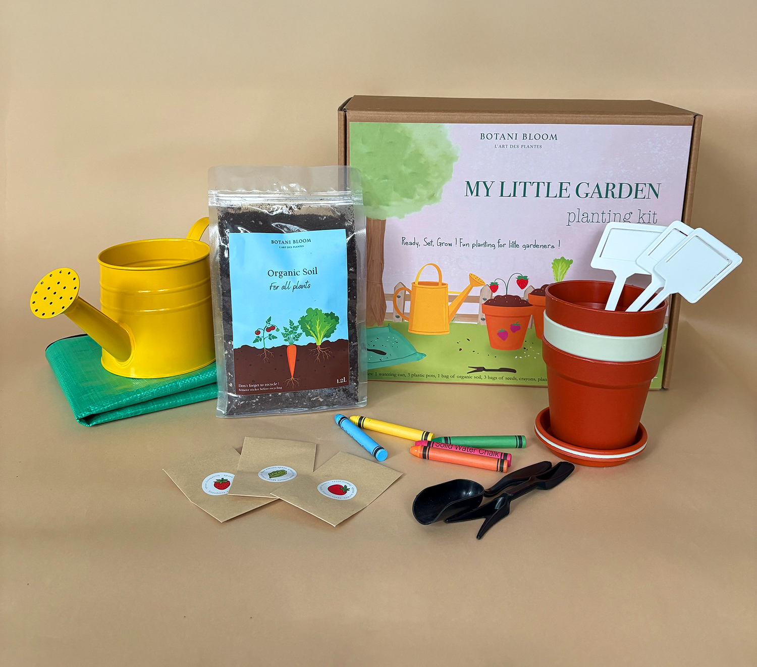 Children's gardening kit with pot, soil, watering can, and tools on a beige background